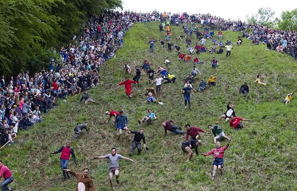 英国数百人为抢奶酪从近200米高山顶冲下，致多人骨折。（网页截图）